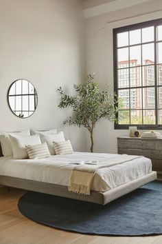 a bedroom with a bed, dresser and round mirror