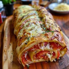 there is a long pizza roll on the cutting board with cheese and tomato slices in it