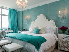 a bedroom decorated in turquoise and white with a chandelier hanging from the ceiling