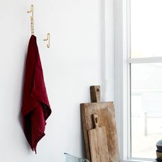 a red towel hanging on the side of a white wall next to a cutting board