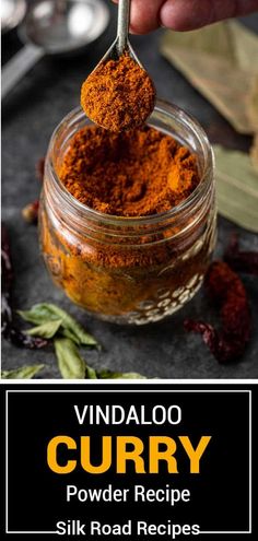 a spoon full of curry on top of a jar filled with powdered vegetables and spices