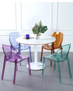 three different colored chairs around a white table