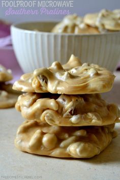 three cookies stacked on top of each other in front of a white bowl filled with peanut butter