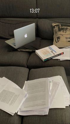 an open laptop computer sitting on top of a couch next to papers and other items