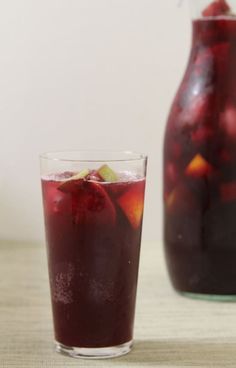 a pitcher and glass filled with liquid sitting next to each other on a table top