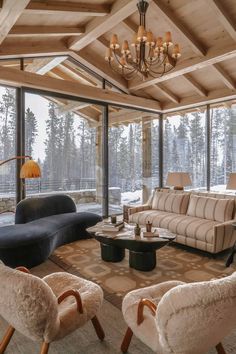 a living room with couches, chairs and tables in front of large glass windows