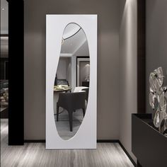 a large white mirror in the middle of a room next to a table and chair