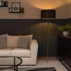 a living room filled with furniture and a lamp on top of a wooden stand next to a coffee table