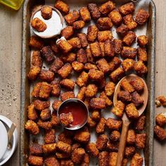 a pan filled with tater tots and dipping sauce