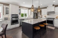 a large kitchen with white cabinets and marble counter tops, an island in the middle