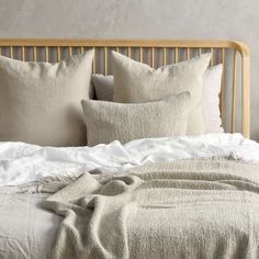 an unmade bed with white linens and pillows