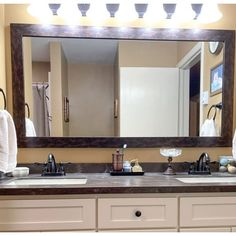 a bathroom vanity with two sinks and a large mirror above it, along with towels hanging on the wall