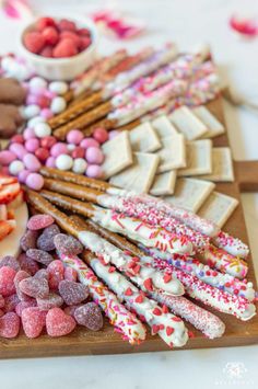 an assortment of different types of candy on a cutting board with strawberries and marshmallows