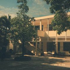 an apartment building with trees in front of it and stairs leading up to the second floor