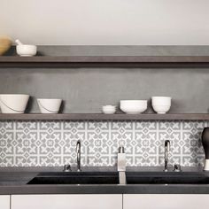 bowls and cups are sitting on the shelf above the kitchen sink