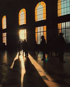 people are standing in an old building with large windows