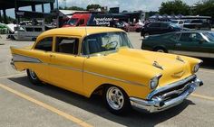 an old yellow car parked in a parking lot