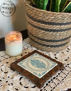 a candle sits on a doily next to a potted plant