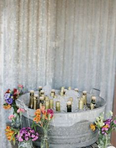 an old metal tub filled with lots of bottles and flowers on top of a wooden table