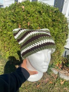 a white mannequin head wearing a green and brown striped crochet hat