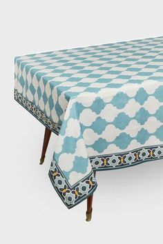 a blue and white table cloth with an ornate design on the top, sitting on wooden legs