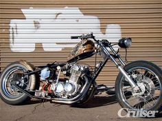 a motorcycle parked in front of a garage door with graffiti on the wall behind it