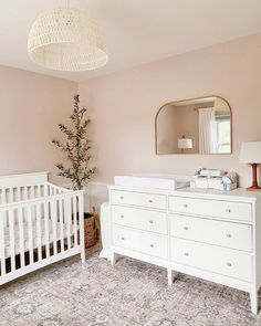 a baby's room with a crib, dresser and mirror on the wall