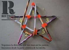 an origami star made out of sticks and colored crayons with numbers written in spanish