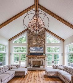 a living room filled with lots of furniture and a chandelier hanging from the ceiling