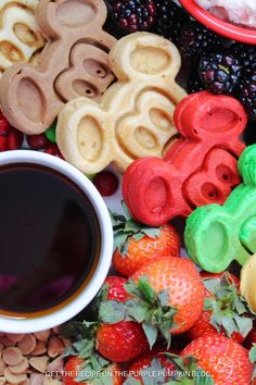 there are many different shaped cookies next to a cup of coffee on the table with berries