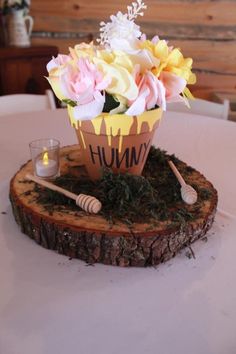 a vase filled with flowers sitting on top of a wooden stump next to a candle