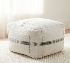 a white square ottoman sitting on top of a rug