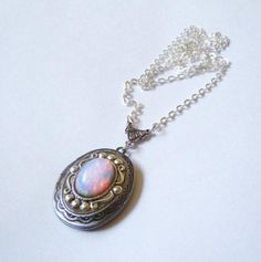 This lovely necklace is made using a vintage glass fire opal. The opal is high quality and features flashes of pink, orange, yellow, and even green... The glass is circular in shape with a flat back and domed front. It is attached to American made, antique silver setting. I set a stunning Beautiful Pink Opal Glass Cabs cabs in a classic oval locket in antiqued silver. The locket has a simple vintage-inspired design engraved on the front and back.  The locket is 1.25" X 1" (3 cm X 2.5 cm) with sp Vintage Opal Jewelry With Oval Cabochon, Vintage Opal Oval Cabochon Jewelry, Vintage Oval Cabochon Opal Jewelry, Handmade Vintage Opal Jewelry, Victorian Opal Oval Jewelry, Victorian Oval Opal Jewelry, Dragons Breath Fire Opal, Oval Locket Necklace, Pink Fire