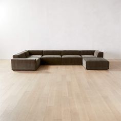 a large sectional couch sitting on top of a hard wood floor next to a white wall