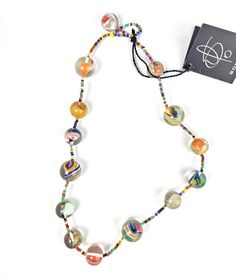 This rare early retired necklace is part of the Preterito Perfeito line and is called Paulinho. Pretérito Perfeito is an upcycling collection, created by reusing the brand's own pieces and small colored objects encapsulated in transparent resin. This favorite collection reaffirms the company's eco-friendly posture of recycling its small flawed, odd or remnant pieces, taking them from the past of other collections to become perfect again in new shapes and designs. This necklace features 14 round Handmade Multicolor Necklaces From Recycled Glass, Handmade Multicolor Necklace From Recycled Glass, Multicolor Recycled Glass Bead Jewelry, Multicolor Recycled Glass Beaded Jewelry, Eclectic Adjustable Necklace With Round Beads, Multicolor Recycled Glass Necklaces For Gifts, Multicolor Recycled Glass Necklace As Gift, Vintage Adjustable Multicolor Necklaces, Artisan Hand-strung Glass Necklaces