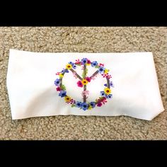 an embroidered peace sign on top of a white pillow