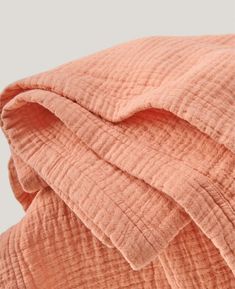 an orange blanket is folded on top of a bed