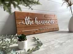 a wooden sign that says the howards on it next to some potted plants