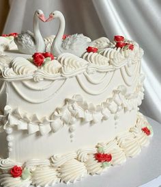 a wedding cake decorated with swans and roses