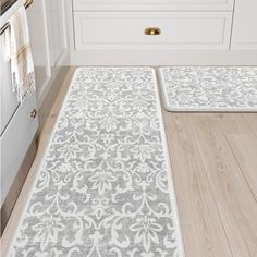 two rugs in the middle of a kitchen with white cabinets and drawers behind them