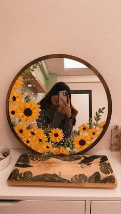 a woman taking a selfie in front of a mirror with sunflowers on it