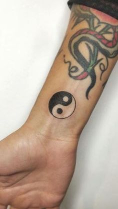 a person with a tattoo on their arm holding onto a small black and white yin sign