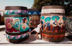 a woman standing in front of some very colorful barrels