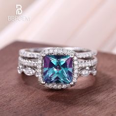 an engagement ring with a blue and purple stone surrounded by diamonds