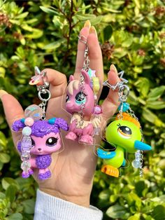 the littlest pet shop keychains are being held by someone's hand