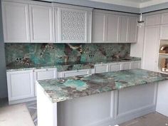 an empty kitchen with white cabinets and green marble counter tops in the middle of the room