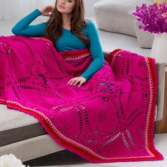 a woman is sitting on a bed with a pink blanket over her head and she is looking at the camera