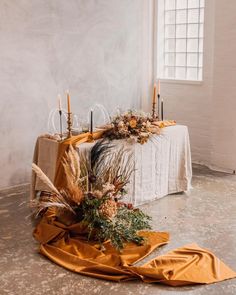 an arrangement of flowers and candles on a table