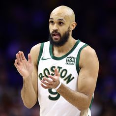 a man with a beard wearing a white and green uniform holding his hands out in front of him