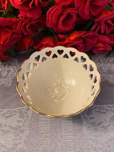 a white bowl sitting on top of a table next to red flowers